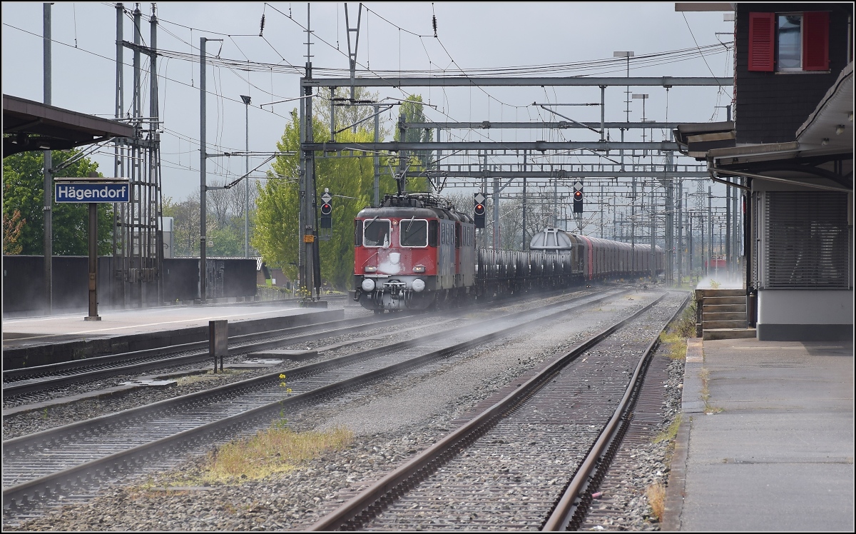 Der Schneefall kurz zuvor sorgt fr heftige Bodennebel in Hgendorf, whrend sich Re 421 384-9 und eine weitere Re 421 mit einem Gterzug nhern. April 2017.