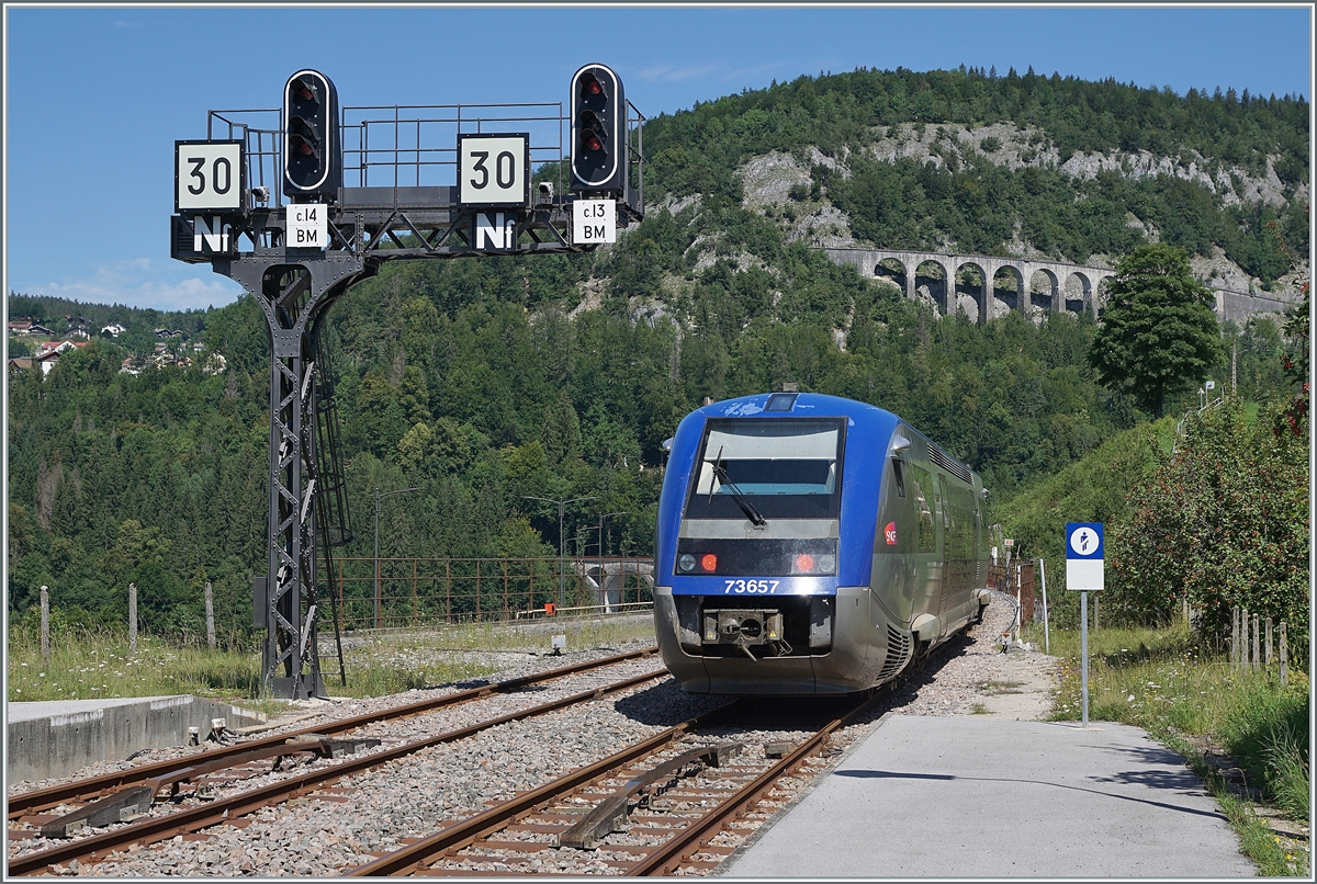 Der SNCF X 73657 verlässt als TER 895511 auf dem Weg von Dole nach St-Claude den Bahnhof von Morez und fährt dabei an der markanten Signalbrücke vorbei, darunter - wie bei französischen Signalen meist üblich ist das Zugssicherungssystem  Crocodil  zu sehen. 
Neben dem 165 Meter langen Viaduc des Crottes im rechten Bildteil ist links vom Triebwagen auch der 238 Meter lange Viaduc de Morez zu erkennen, welchen der Triebwagen in Kürze befährt, wie auf dem ersten heute eingestellten Bild zu sehen ist.

10. August 2021