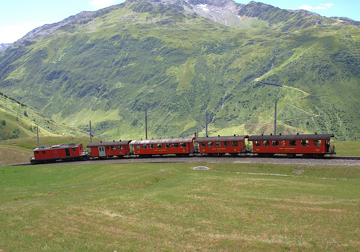 Der Sonderzug zum Jubil�um 100 Jahre FO hat am 05.07.2026 die Station N�tschen verlassen und f�hrt jetzt Richtung Andermatt.
Im Hintergrund ist der Gemsstock zu erkennen.
Das Wagenmaterial geh�rt der Dampfbahn Furka-Bergstrecke. Einige Wagen stammen von der FO.