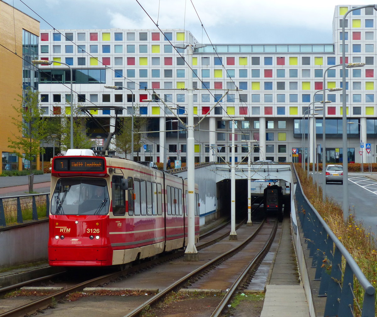 Der Straßenbahntunnel nahe dem Bahnhof Den Haag HS ist mit einem farbenfrohen Haus bebaut, hinter dem die Bahnlinie verläuft. Die verschiedenfarbigen Fenster ergeben interessante Fotomotive auch vom Bahnsteig aus. Fahrzeug 3126 der HTM ist auf dem Weg nach Delft. 25.8.2018, Den Haag