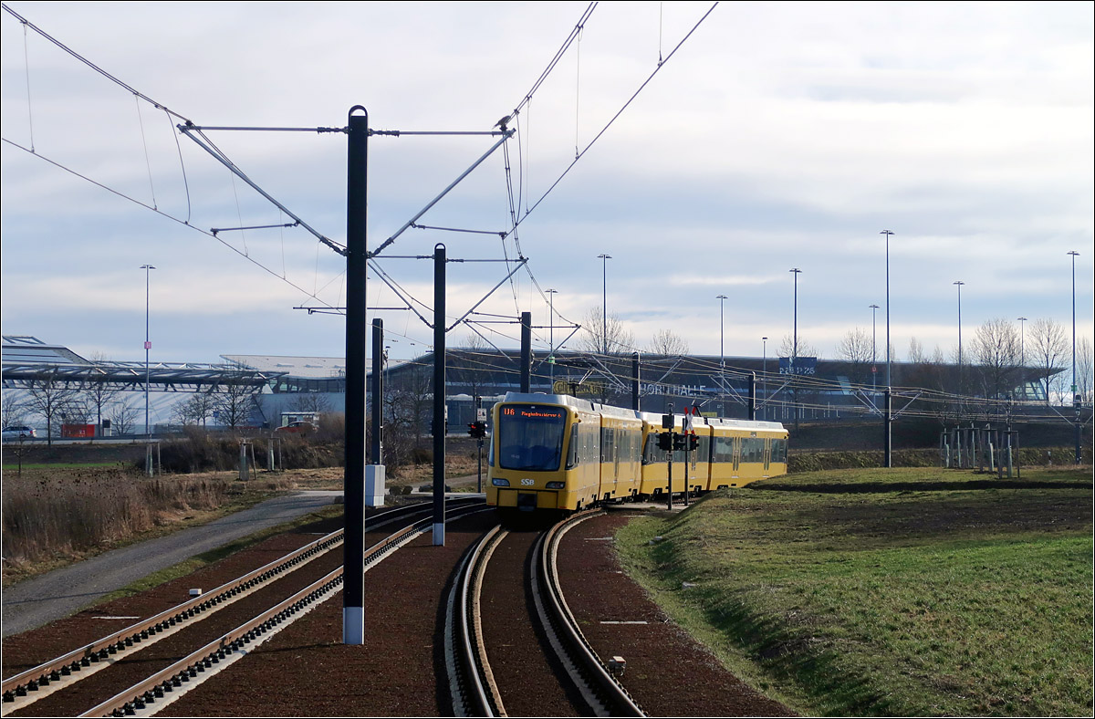 Der Stuttgarter Messe entgegen - 

... fährt dieser Stadtbahnzug auf der Linie U6. Nach der Haltestelle Stadionstraße geht die Trasse in einen Einschnitt über und schmiegt sich an die parallel verlaufende B 27 an um eine Landstraße unter einer schon bestehenden Brücke zu unterqueren. Im Bildhintergrund sind die Messehallen erkennbar.

29.01.2022 (M)