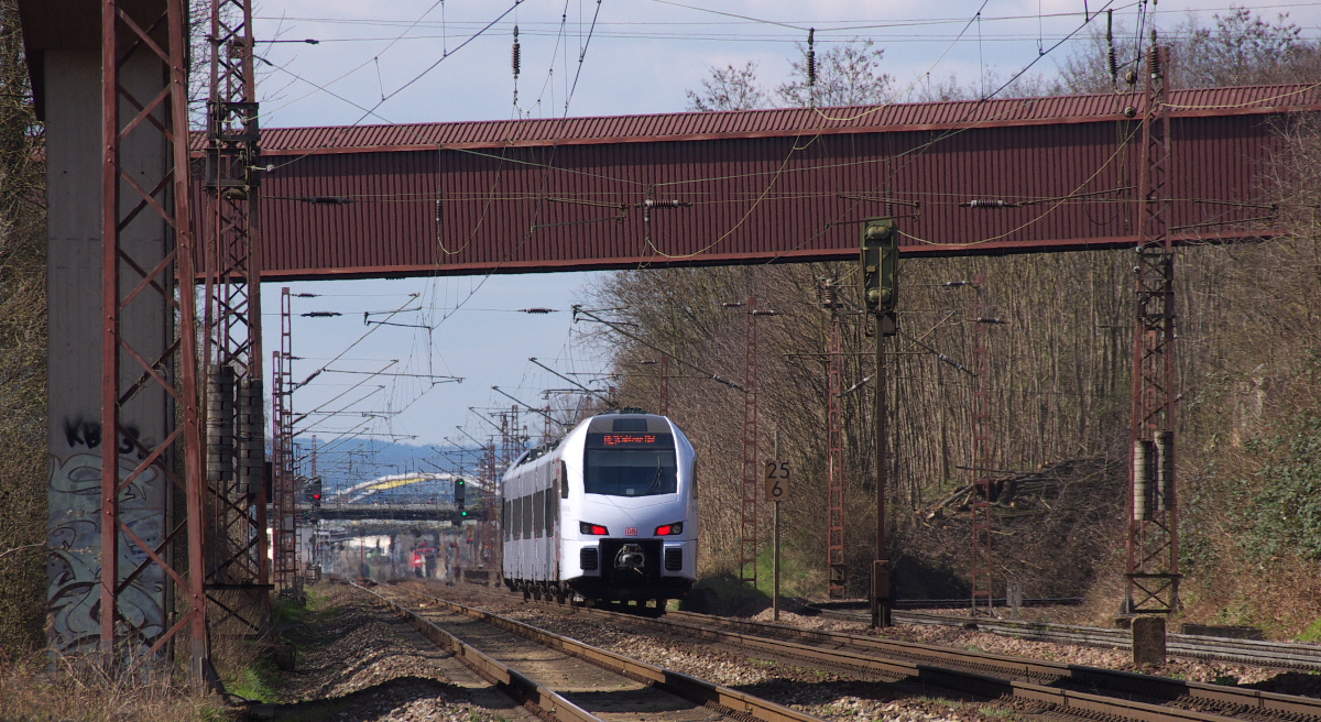 Der SÜWEX braust auf Dillingen zu. In Sichtweite ist schon der Bahnhof von Dillingen Saar. Der Süwex nach Koblenz hat gerade das im Tunnel über das Gleis laufende Förderband vom Hafen Saarlouis/Dillingen zur Zentralkokerei und Hütte unterquert. Nun erfolgt die Überquerung der hafenanschlußbahn und des Flüßchens Prims. Bahnstrecke 3230 Saarbrücken - Karthaus am 05.04.2015