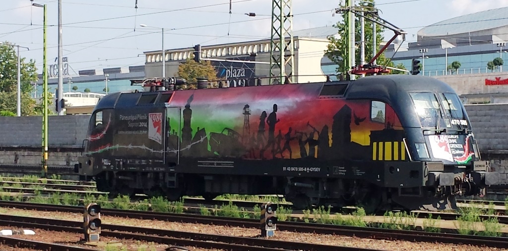 Der Taurus 470 505-8 der GySev stand im Vorfeld des Bahnhofes Budapest keleti-pu am 04.08.2015.
Wenig später wurde die Lok - mit der schicken Lackierung in Gedenken an den Mauerfall vor 25 Jahren - von der, auf einem anderen Foto zu sehen, 448 428 abgeschleppt. Sie schien defekt zu sein.