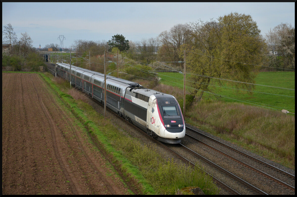 Der TGV Duplex inoui (4701) fuhr als TGV 9677 Paris Est - Karlsruhe am Karfreitag, 29.03.2024, südlich von Schlettstadt (Sélestat) im Elsass mit 220 km/h durch den ehem. Gare du Kaiser. In der Karwoche trug die Wetterlage große Mengen Saharastaub in der Atmosphäre nach Mitteleuropa, s. d. die Lichtverhältnisse trotz strahlendem Sonnenschein getrübt waren. 