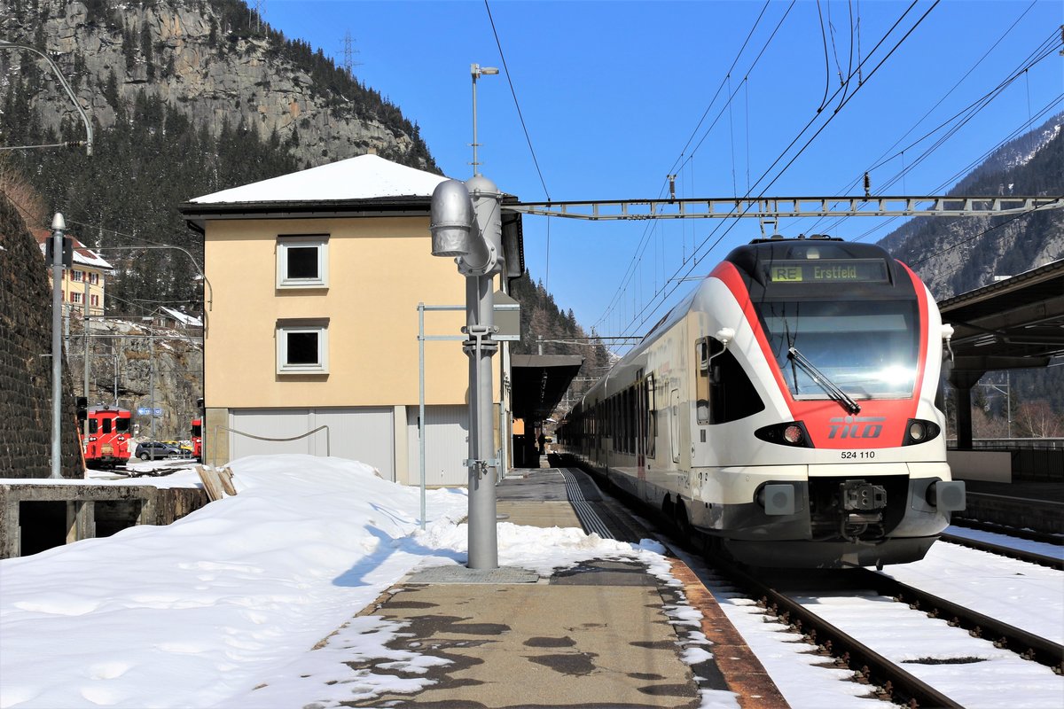 Der TILO RABe 524 110 erreicht am 24. März 2018 als RE Milano C. - Erstfeld den SBB Bahnhof Göschenen. Der MGB Bahnhof Göschenen befindet sich auf der anderen Seite, als der Regio 637 und Regio 639 auf die Abfahrt (12.04 Uhr/12.11 Uhr) nach Andermatt warten. 
