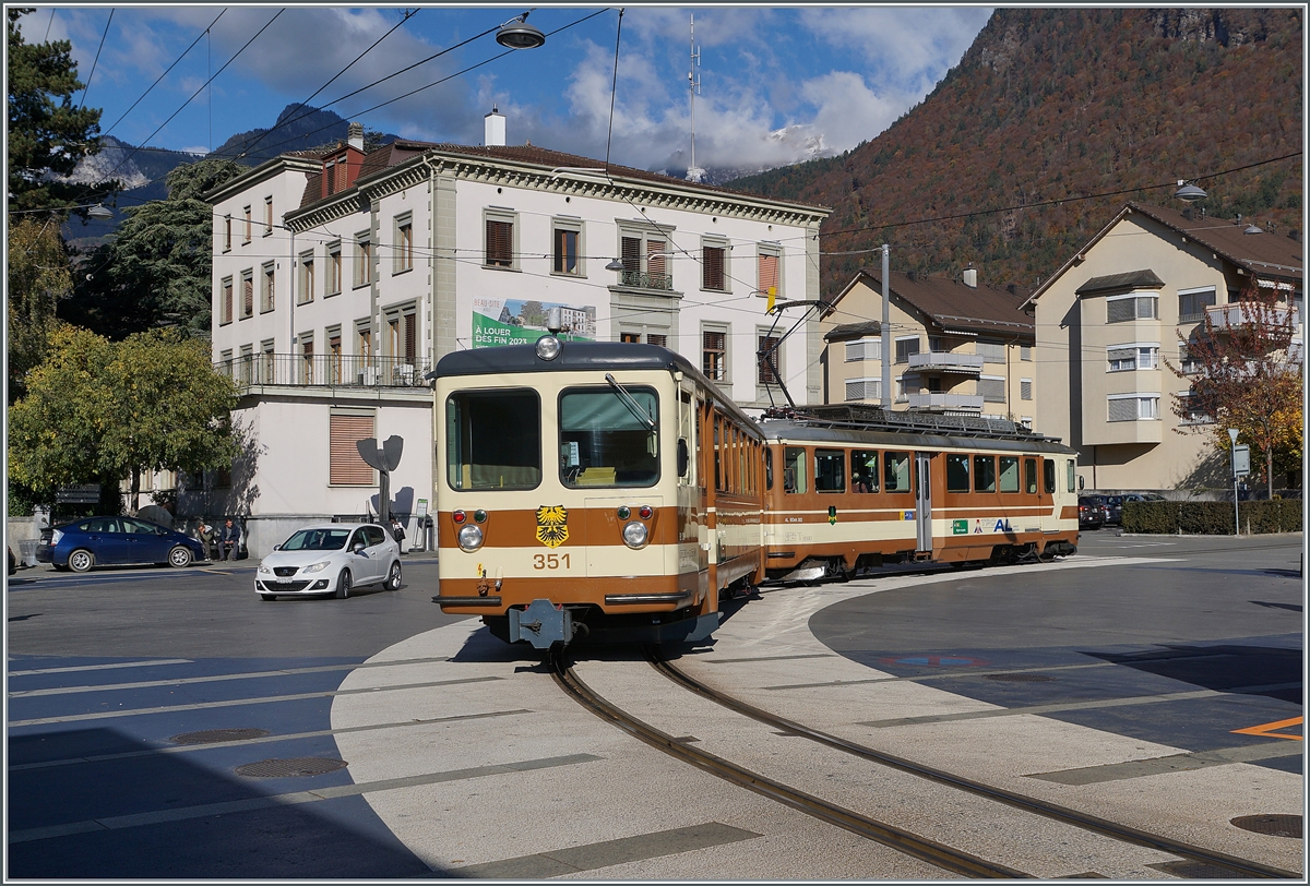 Der TPC A-L BDeh 4/4 302 mit seinem Bt 351 verlässt Aigle in Richtung Leysin. Beide Fahrzeuge tragen noch das A-L Farbschema.

5. November 2021