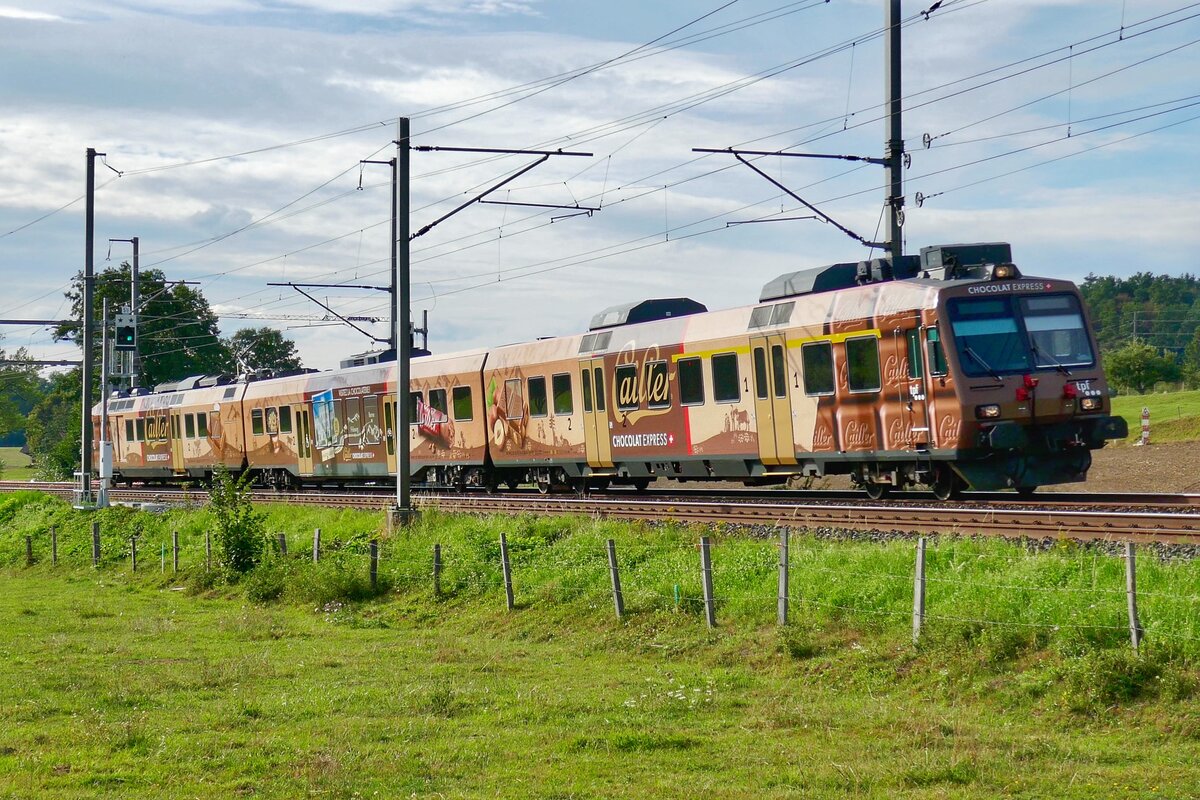 Der TPF  ChocolatExpress  RBDe 560 235 mit dem führenden ABt 884-8 der am 31.8.23 einzel als RE nach Bern unterwegs ist bei Schmitten.
