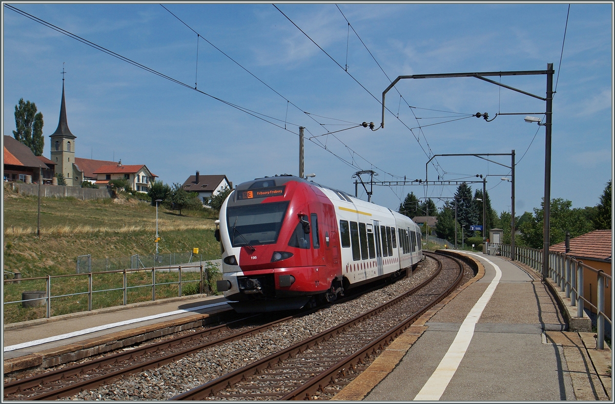 Der TPF RABe 527 195 auf dem Weg von Bulle nach Fribourg bei der Durchfahrt in Neyruz. 
6. August 2015