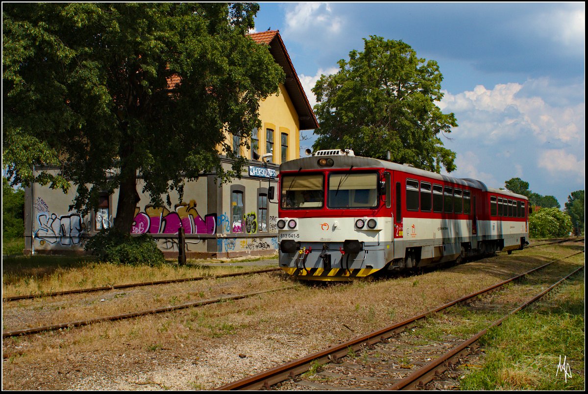 Der Triebzug 813 041 ist eben im Endbahnhof Zahorska Ves angekommen, und wird wenige Minuten später die Rückfahrt nach Zohor antreten.
Interessant ist das schön renovierte Bahnhofsgebäude mit frisch gedecktem Dach aber verblechten Fenstern und der Graffiti-verschmierten Fassade. (23.05.2018)