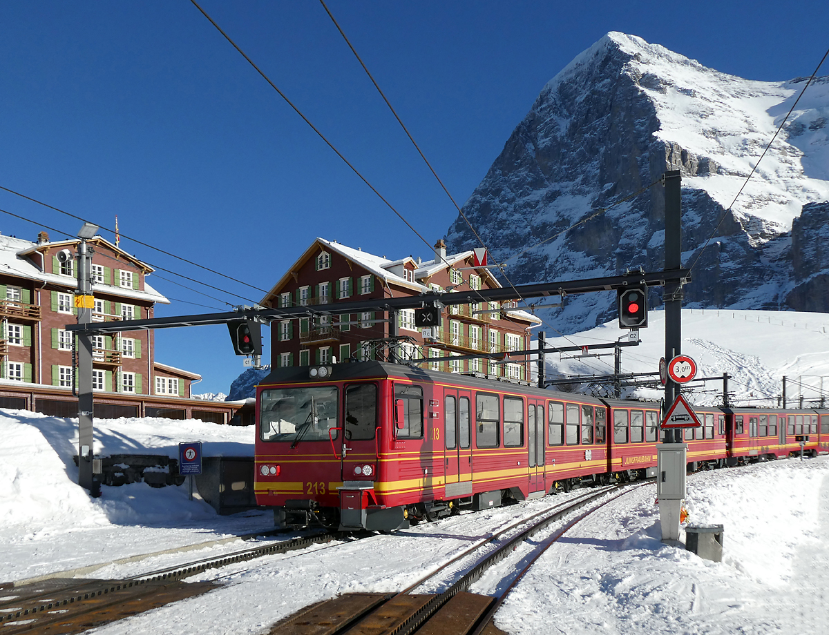 Der Triebzug der Jungfraubahn hat soeben die Station Kleine Scheidegg (2061 müM) verlassen und begibt sich auf die Fahrt nach Eigergletscher. Im Hintergrund ist der Eiger mit der weltberühmten Eigernordwand zu sehen. Kleine Scheidegg, 11.1.2024