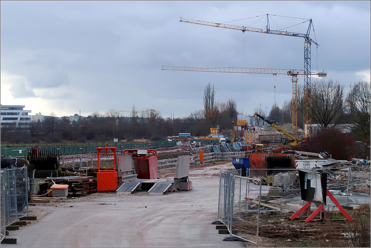 Der U-Bahnweiter nach Gerbersdorf -

Ein weitere Verlängerung der U3 um 2,2 km nach Westen bis Gerbersdorf ist in Bau. Hier ein Blick auf die offene Baugrube der Station Kleinreuth. 
Während der erste Zwischentunnel, der auch die Güterumgehungsbahn von Nürnberg unterfährt mit zweigleisigem Querschnitt bergmännisch aufgefahren wird, werden der zweite Tunnel zwei Einzelröhren bekommen, die ebenfalls bergmännisch entstehen. Diese unterfahren den Rhein-Main-Donau-Kanal. Die Stationen entstehen in offener Bauweise, möglichst nahe unter der Oberfläche. Fahrdynamisch günstig senken sich die Tunnelröhren zwischen den Stationen in größer Tieflagen ab.
Die Wendeanlage westlich der Station Gerbersdorf wird an der Oberfläche liegen. Da wird dann die einzige Stelle entlang der Linien U2 und U3 die am Tageslicht liegt.

Die Frage bleibt, wieso überhaupt für diese Strecke ein Tunnel gebaut wird. liegt sie doch weitgehend unter noch unbebautem Gebiet. Und mit einem Bruchteil der Baukosten hätte man hier ein Straßenbahntrasse bauen können, hätte man ganz auf die U-Bahn in dieser Richtung verzichtet.

18.01.2022 (M)