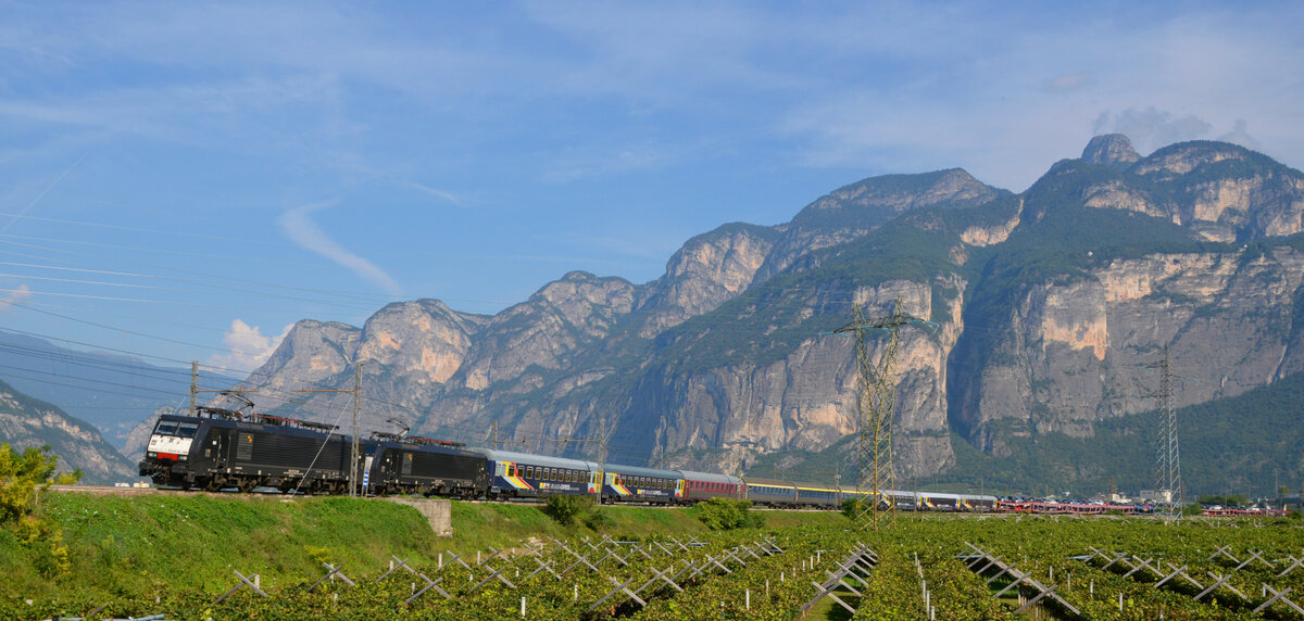 Der URLAUBS-EXPRESS UEx 1385/1395 (Düsseldorf/Hamburg-Altona - Verona Porta Nuova) von Train4you rollt mit rund 2,5 h Verspätung bei Grumo im Trentino durch das Tal der Etsch. 04.09.2021