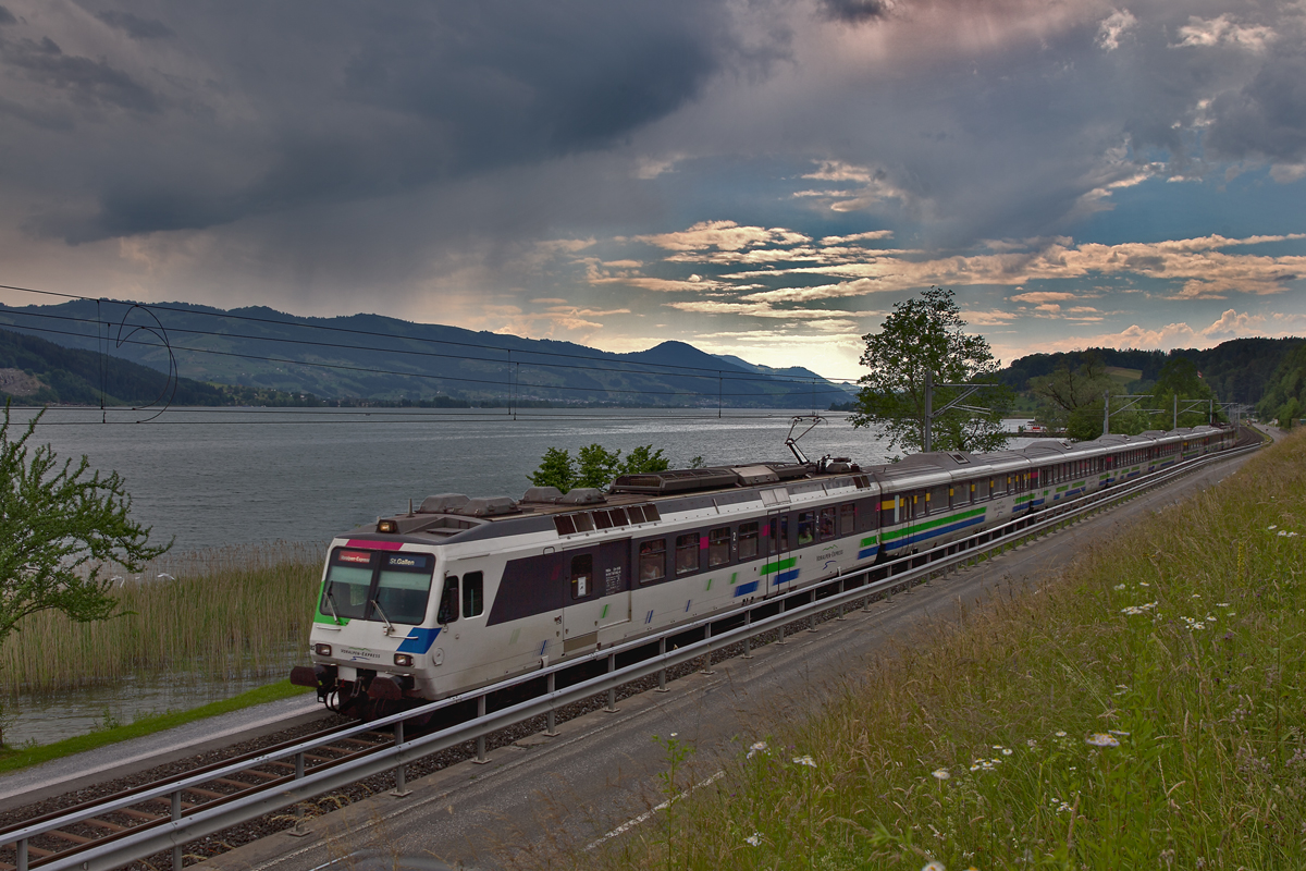 Der VAE Triebzug RBDe 561 082 braust bei aufziehenden leichten Regenschauern in Schmerikon vorüber.Bild vom 1.6.2015