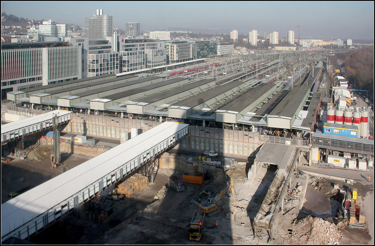 Der verschobene Bahnhof und die Baugrube -

Die bisherigen Bahnsteige des Stuttgarter Hauptbahnhofes wurden ins Gleisvorfeld hinein verschoben um Platz für die Baugrube des Tiefbahnhofes zu machen. Nur ein Teil der alten Überdachung konnte stehen bleiben. Seit einiger Zeit sind die neu gebauten Verbindungsbrücken über die Baugrube in Betrieb. Bislang erfüllten zwei erhalten gebliebene Bahnsteige diesen Zweck. Rechts wird gerade der letzte Rest davon abgerissen. Der Fotostandpunkt ist deutlich an seinem Schatten erkennbar.

06.12.2006 (M)