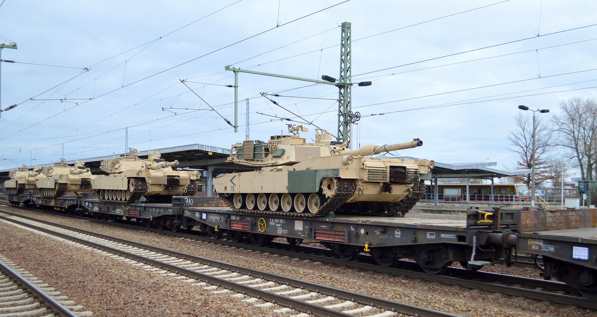 Der vordere Wagen ist der Drehgestell-Flachwagen der DB Cargo mit der Nr. 31 RIV 80 D-DB 4863 307-3 Samms 710 beladen mit einem US-amrikanischen M1A1 Abrams Panzer in typischer Wüsten-Tarnfarbe und dahinter drei weitere am 28.01.19 in einem Militärtransportzug Bf. Flughafen Berlin-Schönefeld.