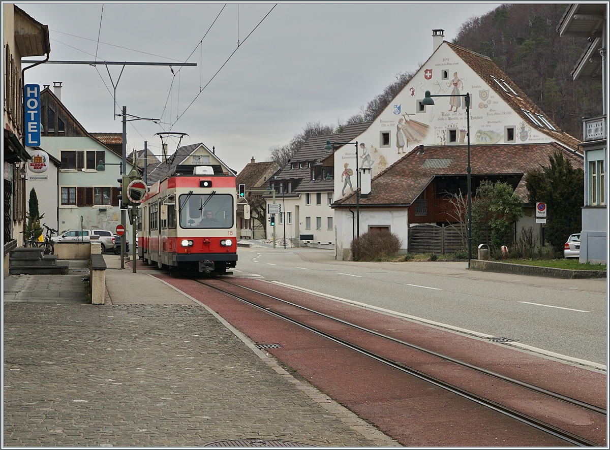 Der Waldenburgerbahn BDe 4/4 16  Liestal  ist mit einem Zug in Richtung Waldenburg im Ort Oberdorf unterwegs, auch hier ist der geringe Platzbedarf der leistungsfähigen und gut ins Dorbild passenden Schamlspurbahn eindrücklich zu erkennen, wobei das durch rote Farbe hervorgehoben Trasse der Bahn der Sicherheit der Passanten und anderer Verkehrsteilnehmer dient. 

21. März 2021