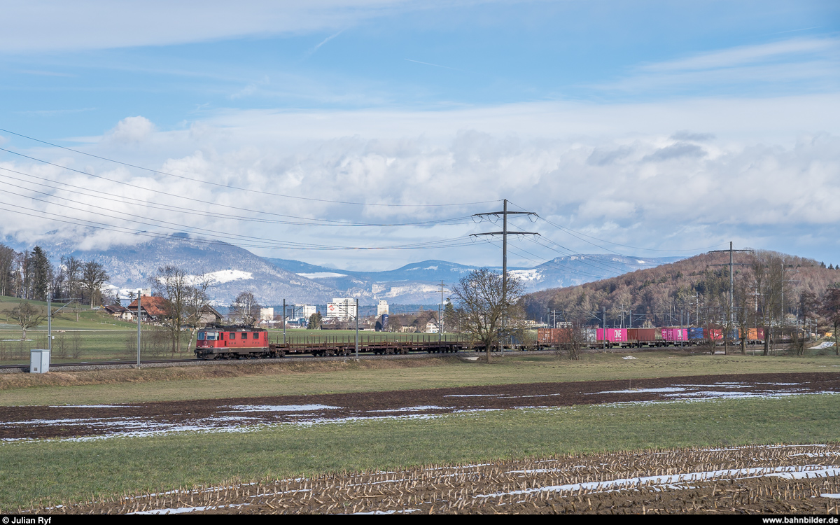 Der von Walter Ruetsch ca. 800 m vorher auf Bild 1131304 gezeigte Güterzug 62228 RBL - Thun GB mit der Re 4/4 III 11355 am 9. Februar 2019 bei Hermiswil. Im Gegensatz zu Walter Bild leider bereits im Wolkenschatten.