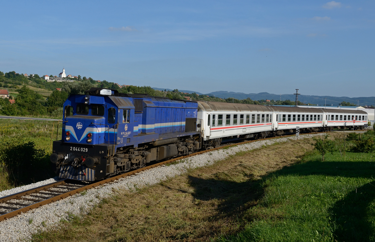 Der Zug 790 von Zagreb Glavni kolod. nach Varaždin war im August 2015 einer der wenigen noch lokbespannten Leistungen in Nordkroatien. Am frühen Abend des 28. August war er zu meiner Freude mit der damals noch in Altlack verkehrenden 2044 029 bespannt und wurde von mir Nahe Novi Marof fotografiert.