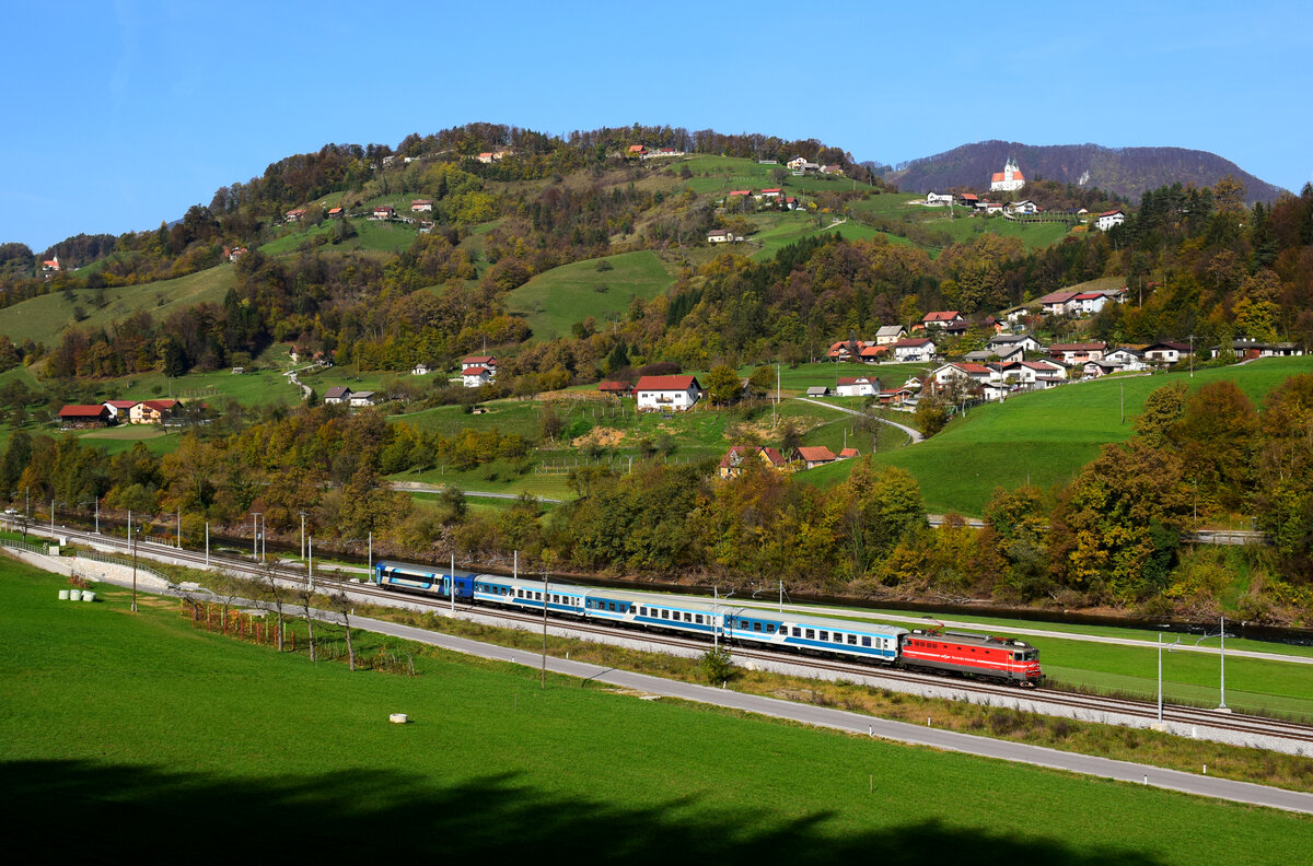 Der Zug MV 247  Citadella  ist auf dem Weg von Ljubljana nach Budapest kurz vor Laško bei Radoblje. Die Kirche auf dem Berg ist Cerkev sv. Mihaela. Die Lok ist eine Altbau 342  Moped 
Radoblje, 30.10.2022.