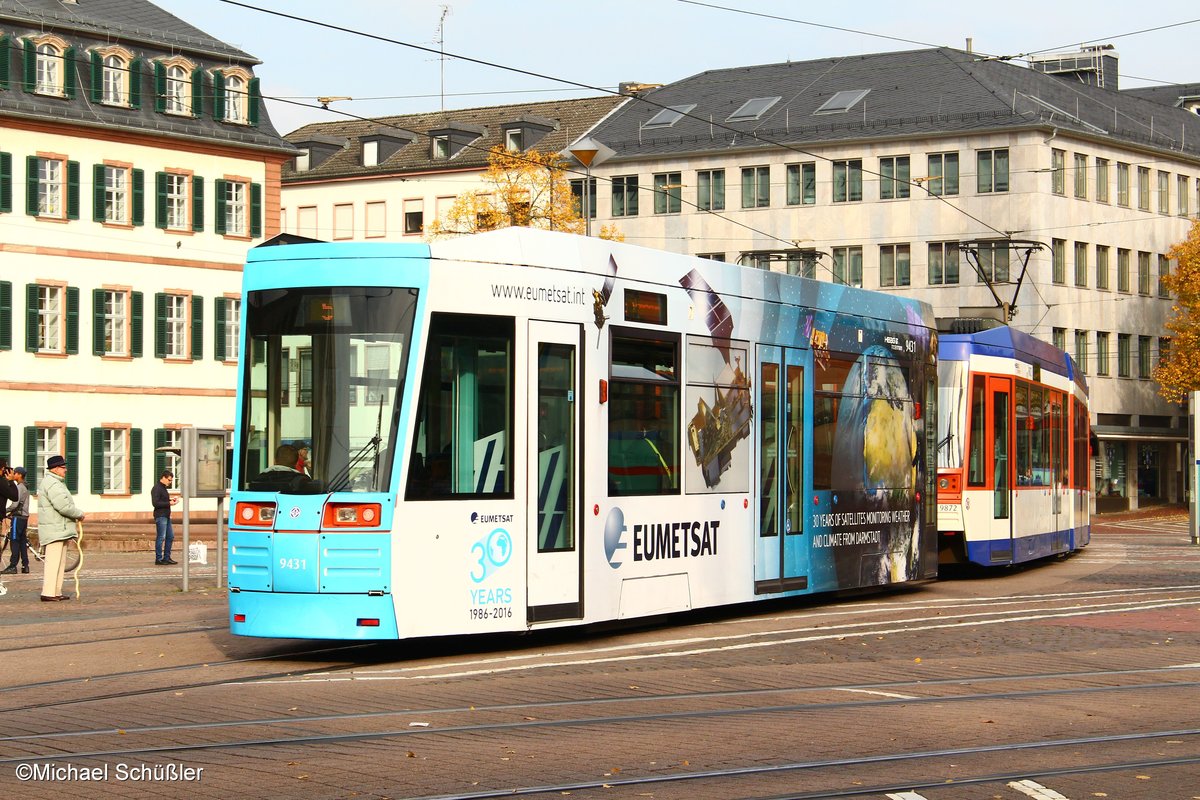 Der zum Anlass des 30jährigen Bestehens der in Darmstadt ansässigen  Europäischen Organisation für die Nutzung meteorologischer Satelliten  ( EUMETSAT ) mit einer auffälligen Beklebung versehene SB 9-BW 9431 fährt am 23.10.2016 hinter ST 13-Tw 9872 als Linie 5 auf dem Luisenplatz ein.