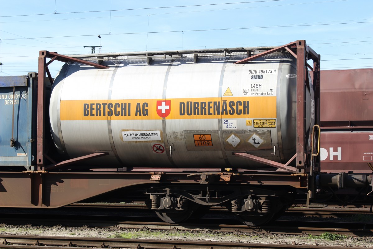 Detailaufnahme von einem Containertragwagen Sgns mit einem aufgesetzten Tankcontainer der schweizer Bertschi AG. Das Ladegut 2,4-Toluylendiamin(Warntafel 60/1709) ist ein wichtiges Zwischenprodukt zur Herstellung von Kunst- und Farbstoffen. Der Wagen war am 18.10.2014 in einen abgestellen Chemikalienzug im Güterbahnhof Köln-Eifeltor eingereiht.
