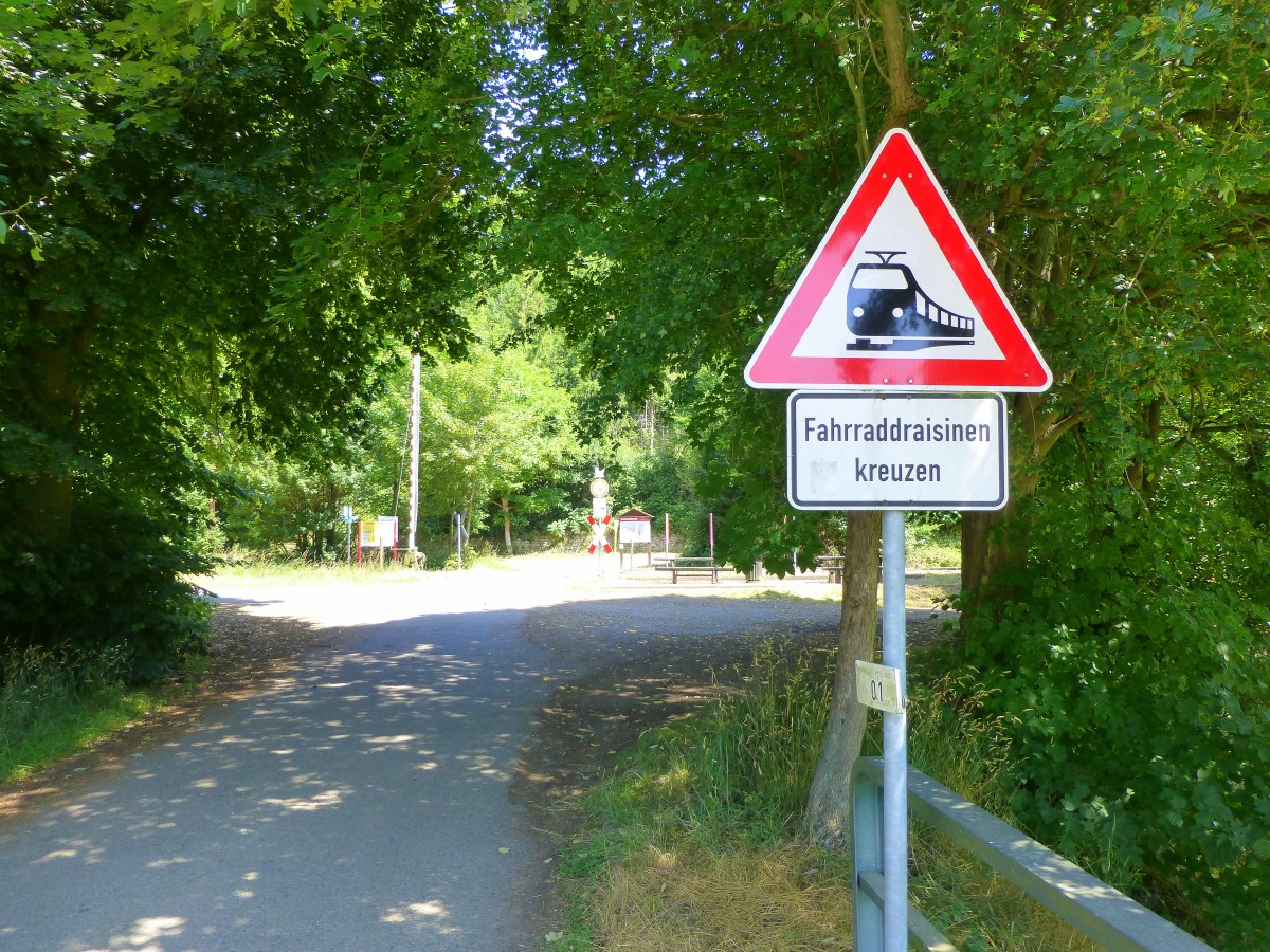 Deutschland, Rheinland-Pfalz, Rehborn. Auf der stillgelegten Bahnstrecke Staudernheim - Lauterecken - Altenglan kann man im Sommer mit gemieteten Fahrraddraisinen das Glantal erkunden. Der Bahnübergang wird mit diesem Schild, das an einen ET erinnert, auf dem Glan Radweg angekündigt. 03.07.2014