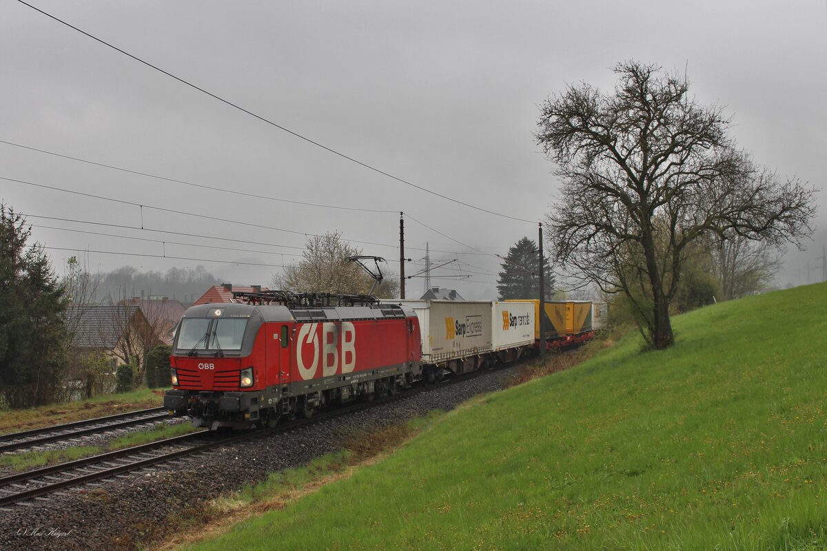Dicke Wolken hängen am 18.4.2023 über den Bergen des unteren Ennstals während die 1293 010 mit dem  GARTNER -Zug SKGAG42244 von Tarvisio Boscoverde nach Lambach in Lahrndorf auf die Kreuzung mit einem Regionalzug wartet.
