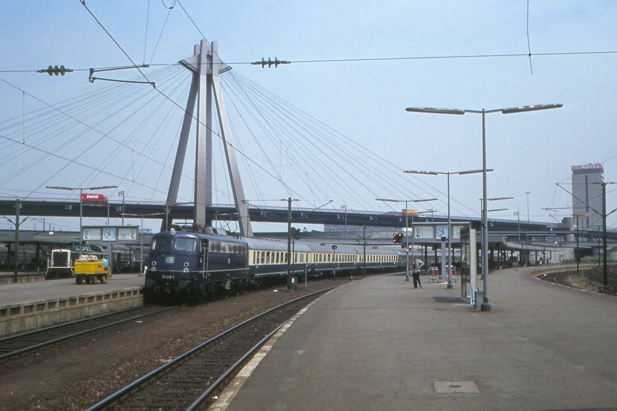 Die 110 319 legt mit dem Schnellzug München - Trier einen Halt in Ludwigshafen am Rhein ein. Stand das Kobaltblau der Bügelfalten-110 nicht besonders gut? 
Links am Bildrand steht eine Diesellok 211 oder 212 in ozeanblau/beige.
Ludwigshafen (Rhein) Hbf, 5. Juni 1978
