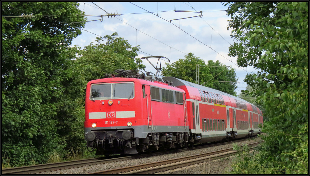 Die 111 127-7 ist mit den Wupper Express (RE 4) nach Aachen unterwegs. Hier zu sehen im Gleisbogen auf der Kbs 485 bei Rimburg,unweit von Übach Palenberg am 14.August 2015.