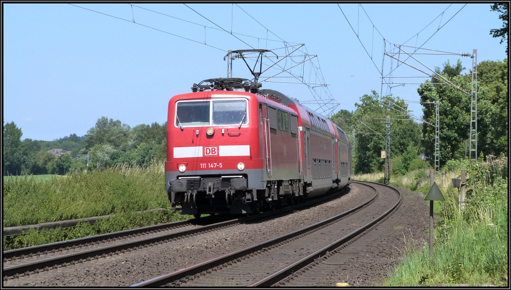 Die 111 147-5 ist mit dem Wupper Express (RE4) unterwegs nach Aachen. Hier wurde der Zug am Bahnübergang bei Rimburg bildlich erfasst. Szenario vom 17.Juli 2015.