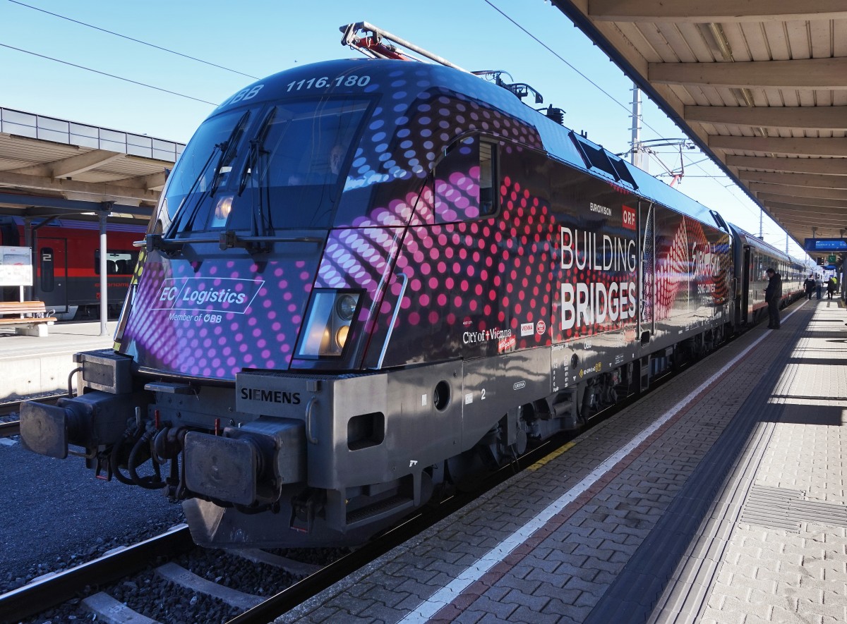 Die 1116 180-1  BUILDING BRIDGES  schiebt soeben die drei vom EC 213  Mimara  aus Zagreb Glavni kol. übernommenen Kurswagen, zum EC 113 (Klagenfurt - Frankfurt (M) Hbf). Aufgenommen am 11.2.2016 in Villach Hbf.