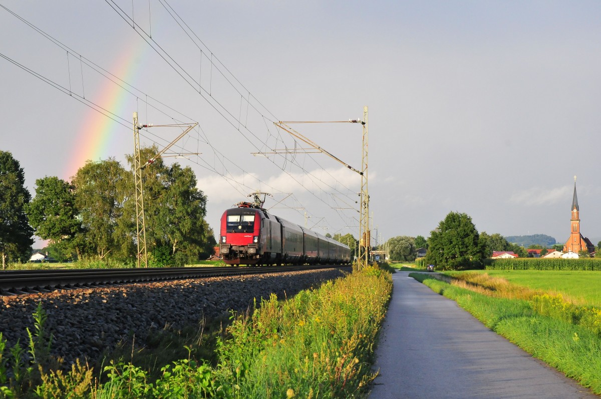 Die 1116 214 der ÖBB vor einem Railjet mit Regenbogen im letzten Abendlicht am 15.08.14 bei Übersee am Chiemsee. 