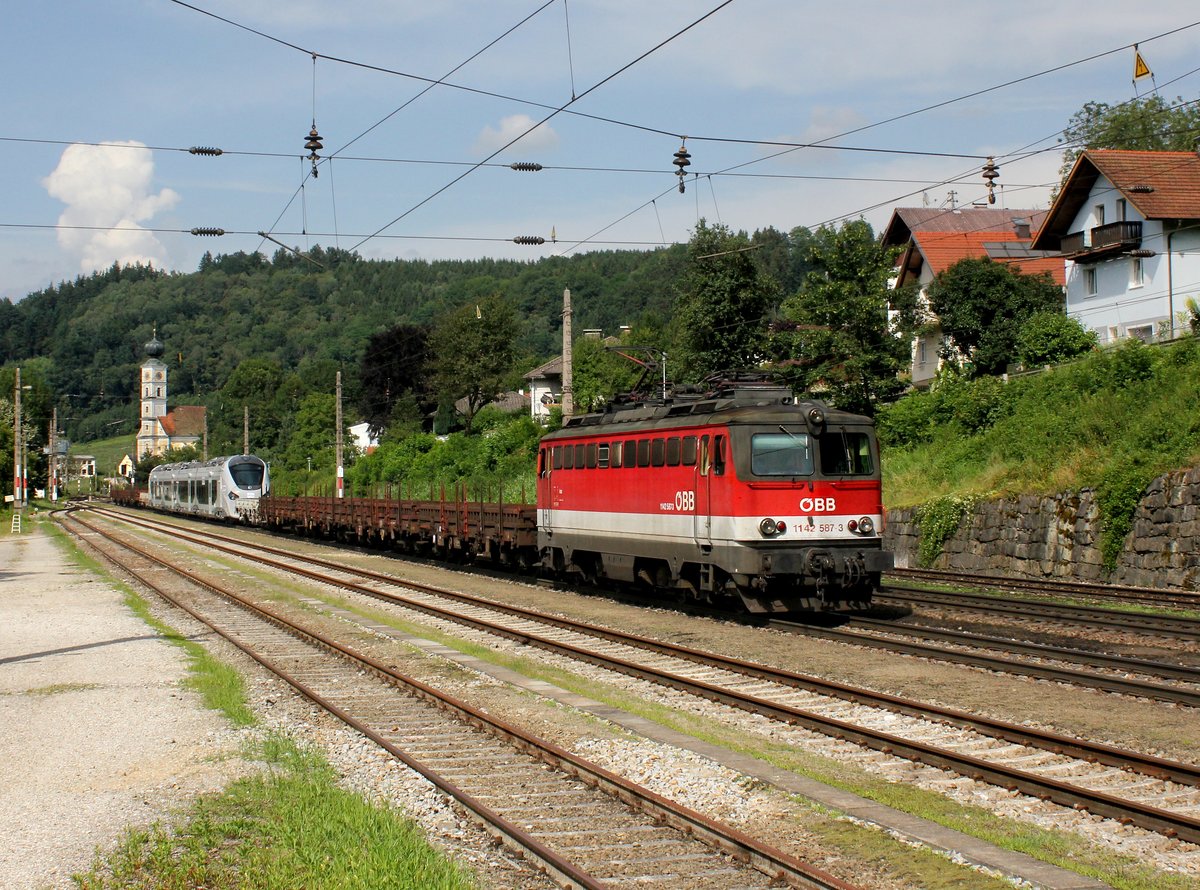 Die 1142 587 mit einem Überführungszug am 23.07.2016 bei der Durchfahrt in Wernstein.