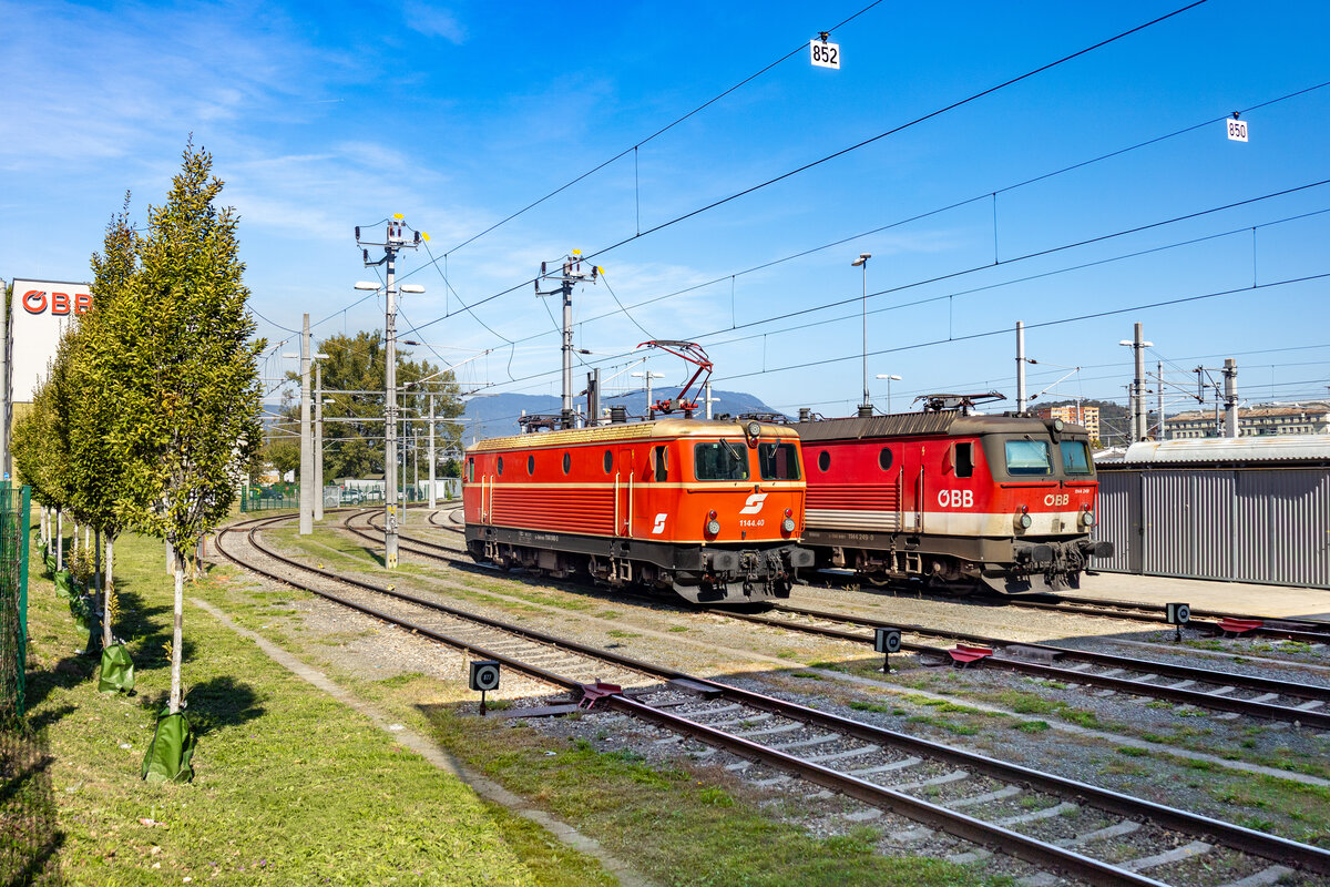 Die 1144 040 ist eine von wenigen Lokomotiven der Reihe 1144, welche bis zuletzt eine Sonderlackierung trugen. Die besagte Lok tr�gt neben dem historischen Design in blutorange-elfenbein noch das Pflatsch. Am 01.10.2026 steht diese allerdings wegen technischer Gebrechen abgestellt in Graz. Eine Schwesterlok im aktuellen Design gesellt sich dazu.