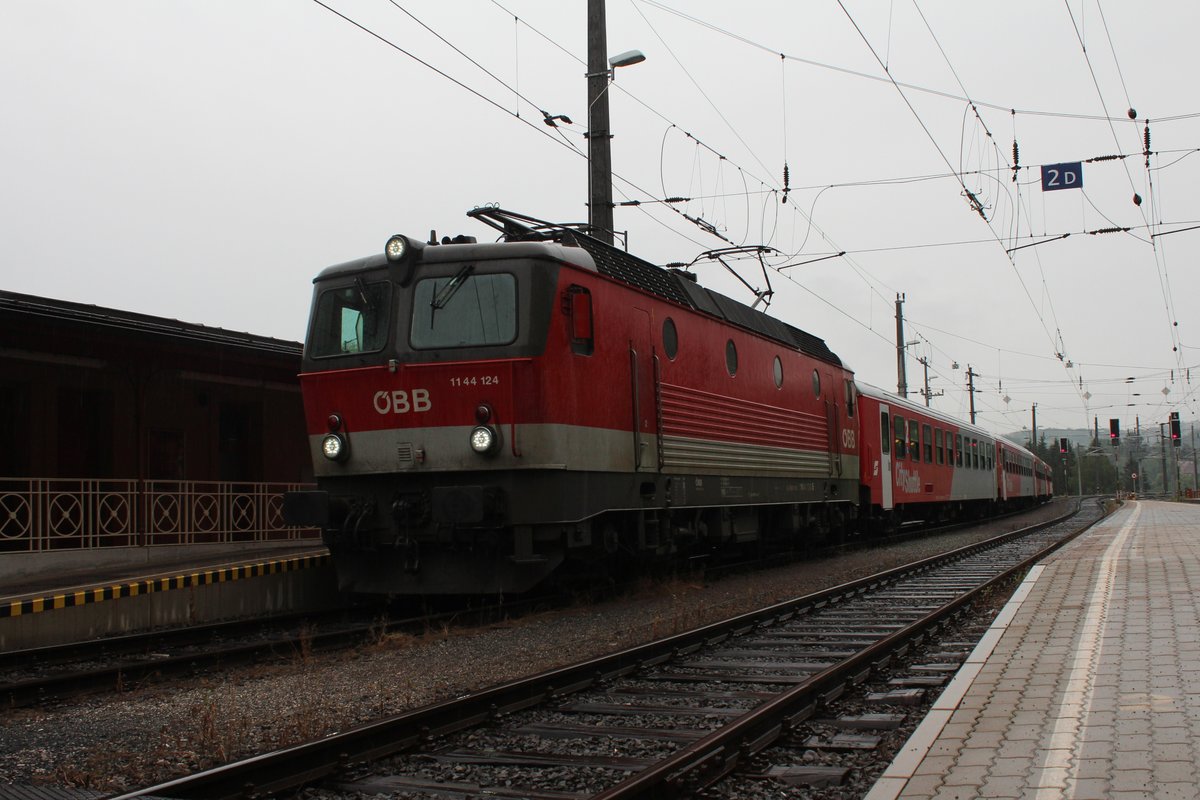 Die 1144 124 steht am verregneten 11.7.2018 in mit dem R4122 von Spielfeld-Straß nach Graz Hbf und wartet auf die Abfahrt in Spielfeld-Straß.
Recht selten stehen am Bahnsteig 1 in Spielfeld-Straß elektrisch traktionierte Züge, da dieser Bahnsteig bereits im slowenischen Bereich der Oberleitung ist. Weil alle drei Oberleitungsbereiche des Bahnhof umgeschalten werden können auf österreichisch oder slowenisch war dieser seltene Fall kein Problem.
Grund für den Einsatz war die baustellenbedingte Sperre der Radkersburgerbahn und auch die Strecke von Spielfeld-Straß nach Maribor war gesperrt.