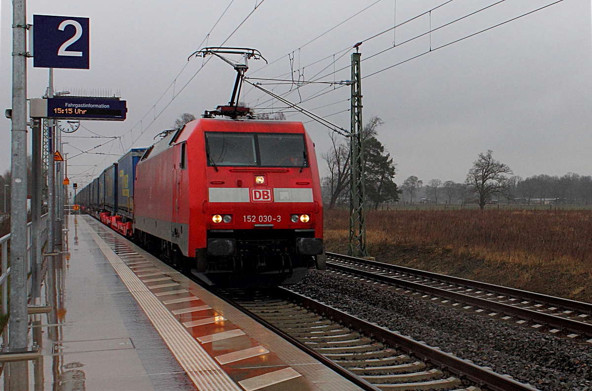 Die 152 030-3 mit einem Taschenwagenzug bei der Durchfahrt am 25.03.2016 in Nassenheide.