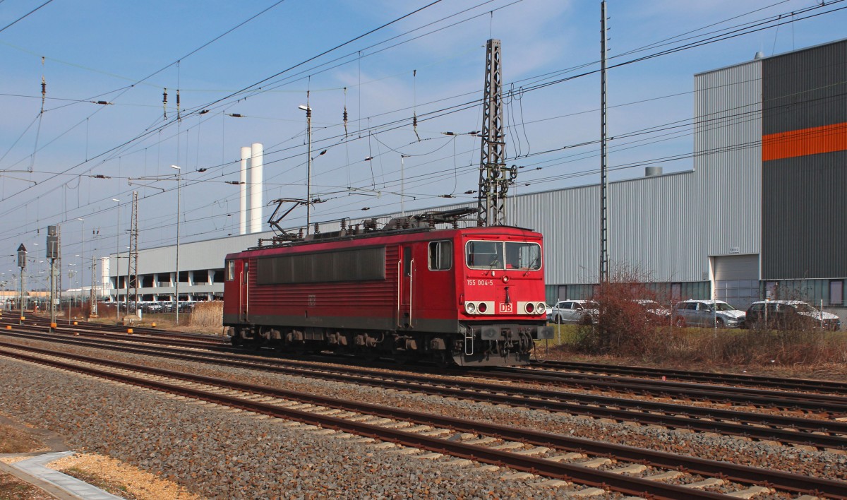 Die 155 004-5 hat am 27.02.2016 den GA 52811 (Braunschweig Rbf - Mosel) im VW-Werk in Mosel abgeliefert und fährt jetzt LZ nach Zwickau zur Wochenendruhe. Im Hintergrund erkennt man die Halle 8 und Halle 9. In der Halle 8 ist das Fahrzeugfinish beheimatet, wo etwaige Fehler von der Produktion ausgebessert oder auch einzelne Teile erneuert werden. In der Halle 9 befindet sich die Fahrzeugverladung auf Eisenbahnwaggons. Standort öffentlich zugänglich.