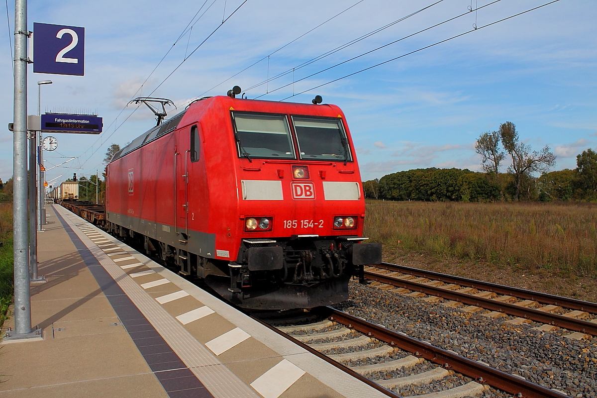 Die 185 154-2 mit einem Taschenwagenzug mit Aufliegern der Firma DB-Schenker am 08.10.2014 bei der Durchfahrt in Nassenheide, da wird es gleich heftig luftig.