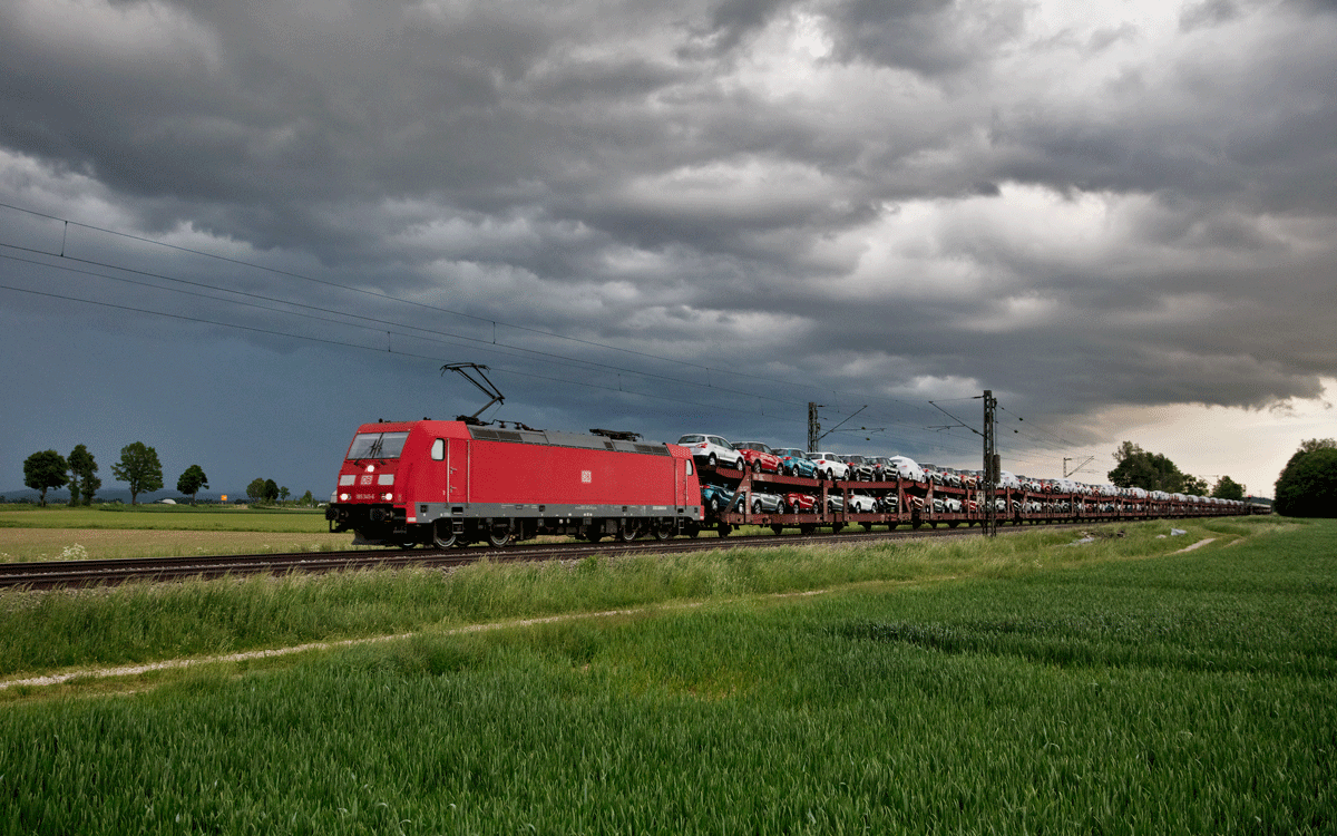 Die 185 345-6 fährt bei einem aufziehenden Gewitter mit einem Autozug in Langenisarhofen vorüber.Bild vom 24.5.2017
