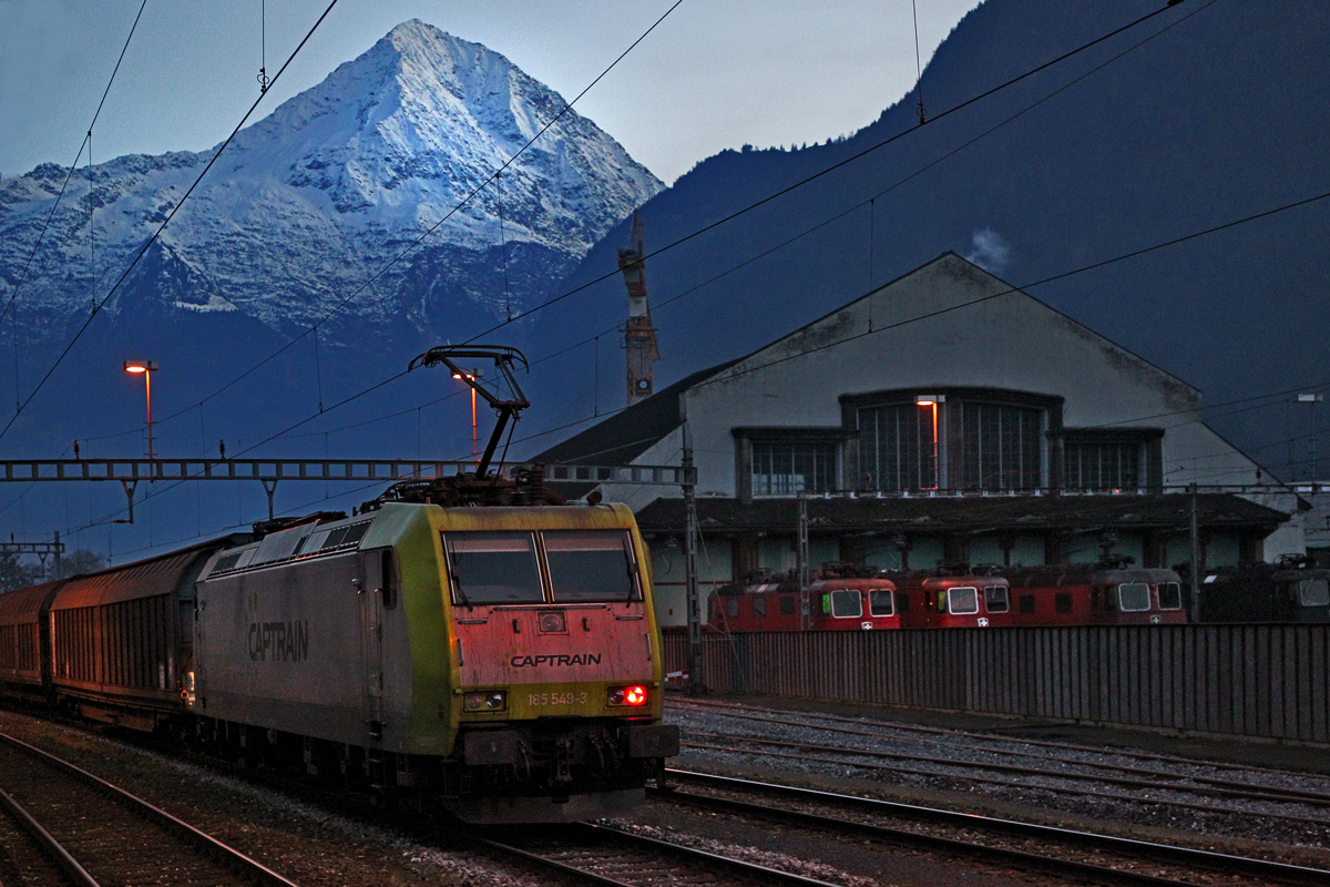 Die 185 549-3 der Captrain Deutschland Gmbh zu sehen vor dem Lokschuppen Erstfeld,leistet abends den  22.11.2014 den Schubdienst an einem Ganzzug über den Gotthard nach Süden.