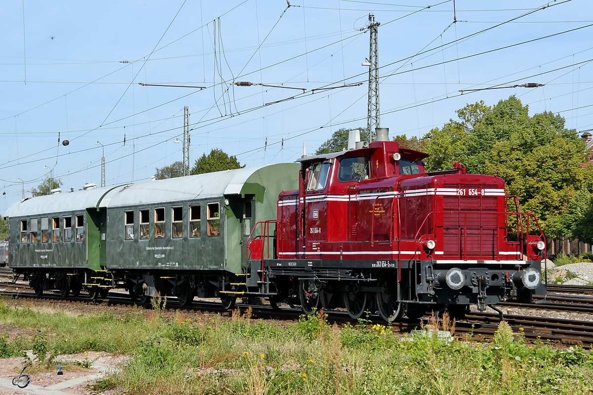 Die 1959 bei MaK gebaute Diesellokomotive 261 654-8 ist mit zwei Prsonenwagen in Darmstadt-Kranichstein unterwegs. (September 2019)