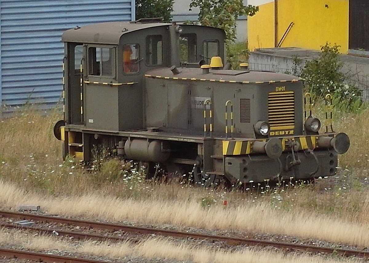Die 1959 von Deutz an die Bundeswehr ausgelieferte Diesellok, Typ A12L 614, Werknr. 56996, wird seit 2006 bei einem Schrott-/Metallrecycling-Betrieb in Biberach (Riß) eingesetzt. Am 28.07.2015 stand die mit einem luftgekühlten 12 Zylinder V-Motor mit 16 l Hubraum ausgestattete, 200 PS starke und 28 t schwere Diesellok außerhalb des Betriebsgeländes und wurde von der Fußgängerbrücke in der Nähe des Bahnhofs Biberach (Riß) aus fotografiert.