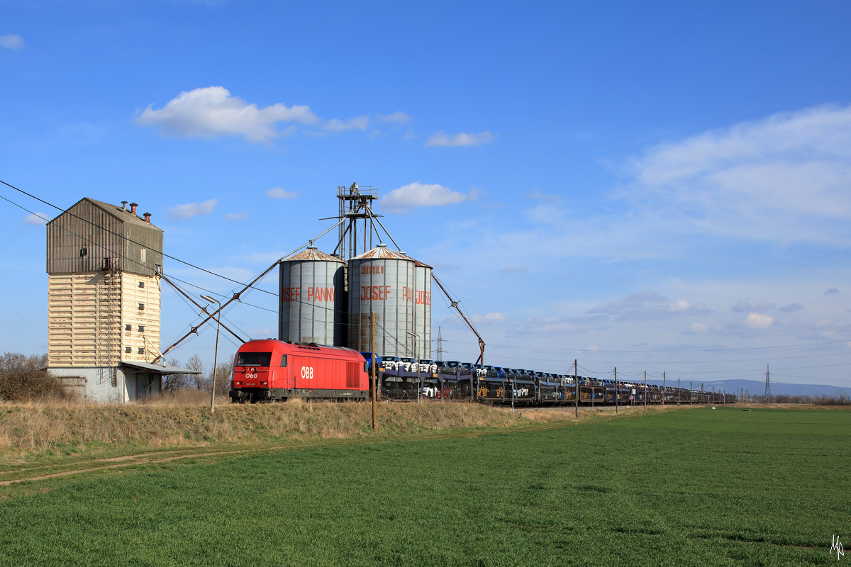 Die 2016.021 durchfährt mit einem Ganzzug aus Autotransportwagen gerade die ehemalige Haltestelle Stripfing. (14.03.2020)