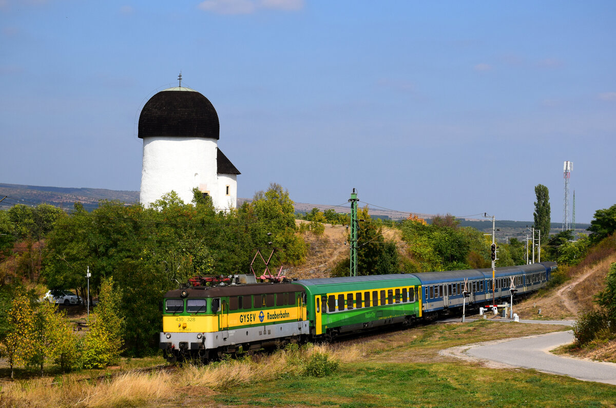 Die 328er GySEV Szili ist schon auf dem Rückweg nach Szombathely verlässt Öskü mit dem Zug IC 9004. Kann man das  Rotunda  (die romanische Rundkirche aus dem 11. Jahrhundert) im Hintergrund zu sehen.
Öskü, 26.09.2021.