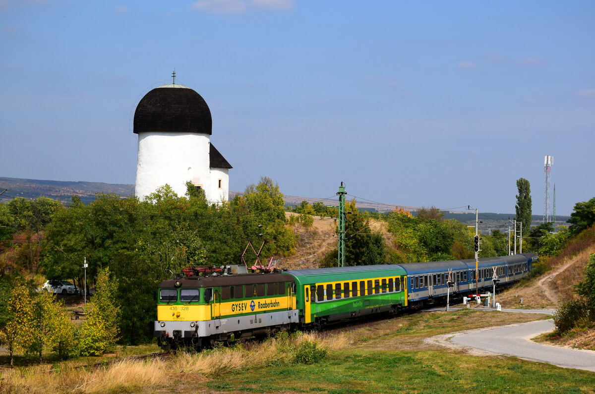 Die 328er GySEV Szili ist schon auf dem Rückweg nach Szombathely verlässt Öskü mit dem Zug IC 9004. Kann man das  Rotunda  (die romanische Rundkirche aus dem 11. Jahrhundert) im Hintergrund zu sehen.
Öskü, 26.09.2021.