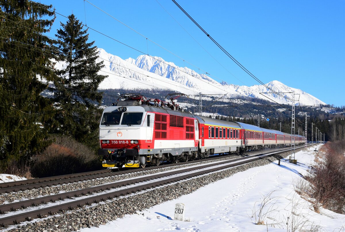 Die 350 018 mit dem Zug Ex 604  Tatran  fährt an den Gipfeln der verschneiten Tatra vorbei in Richtung Bratislava kurz nach Štrba.
20.01.2024.