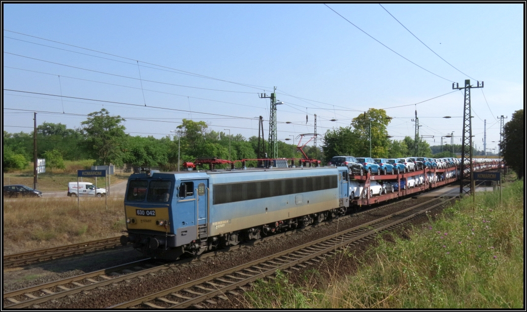 Die 630 042 (V 63) der MAV ist mit einen Autotransportzug aus Esztergom unterwegs nach Györ. Bildlich festgehalten wurde das Szenario Anfang August 2015 am westlichen Stadtrand von Komárom(H).