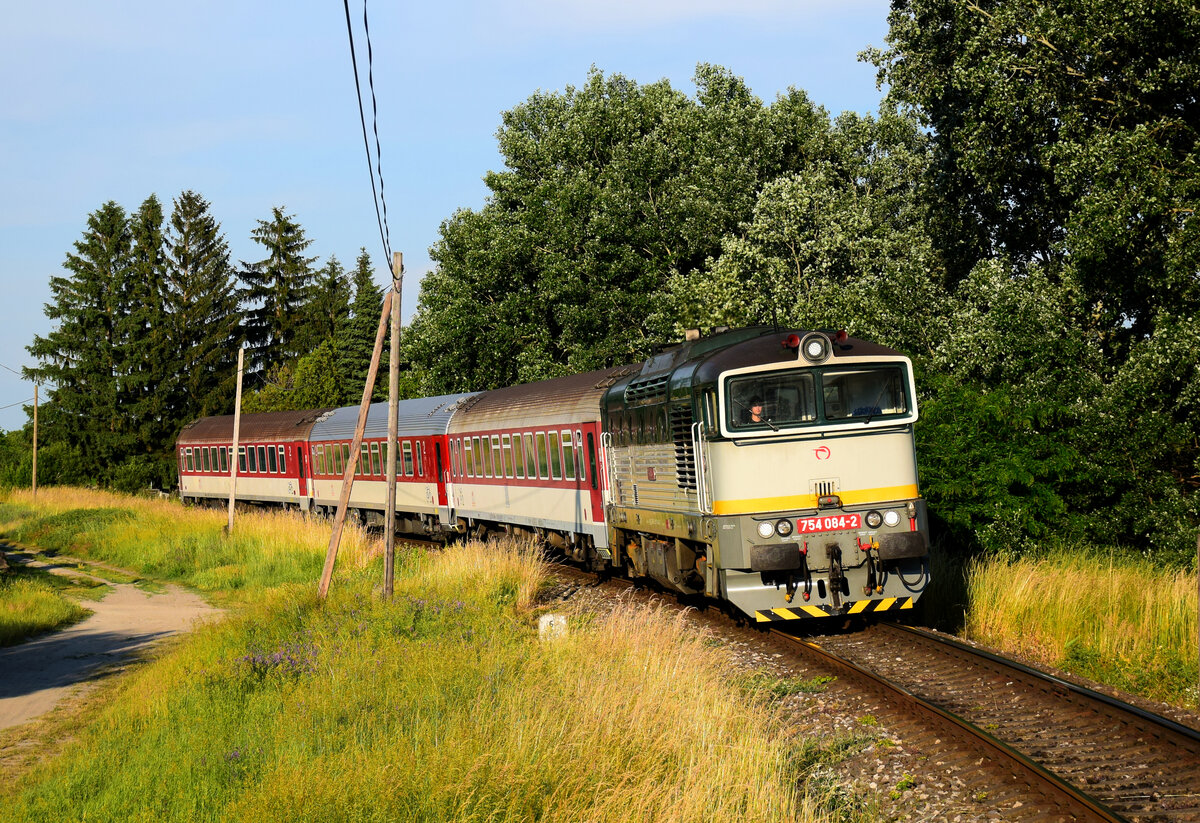 Die 754 084 (Okuliarnik - Taucherbrille) mit dem Personenzug 4362 von Komárno nach Dunajská Streda kurz vor Nová Stráž. Nová Stráž, 11.06.2021.