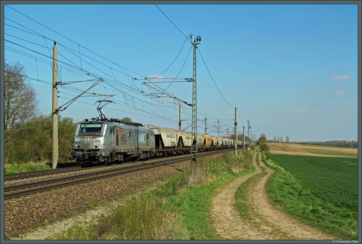 Die Akiem-Mietlok 37025 ist am 19.04.2015 bei Wellen für HSL-Logistik vor einem Getreidezug Richtung Niedersachsen im Einsatz.