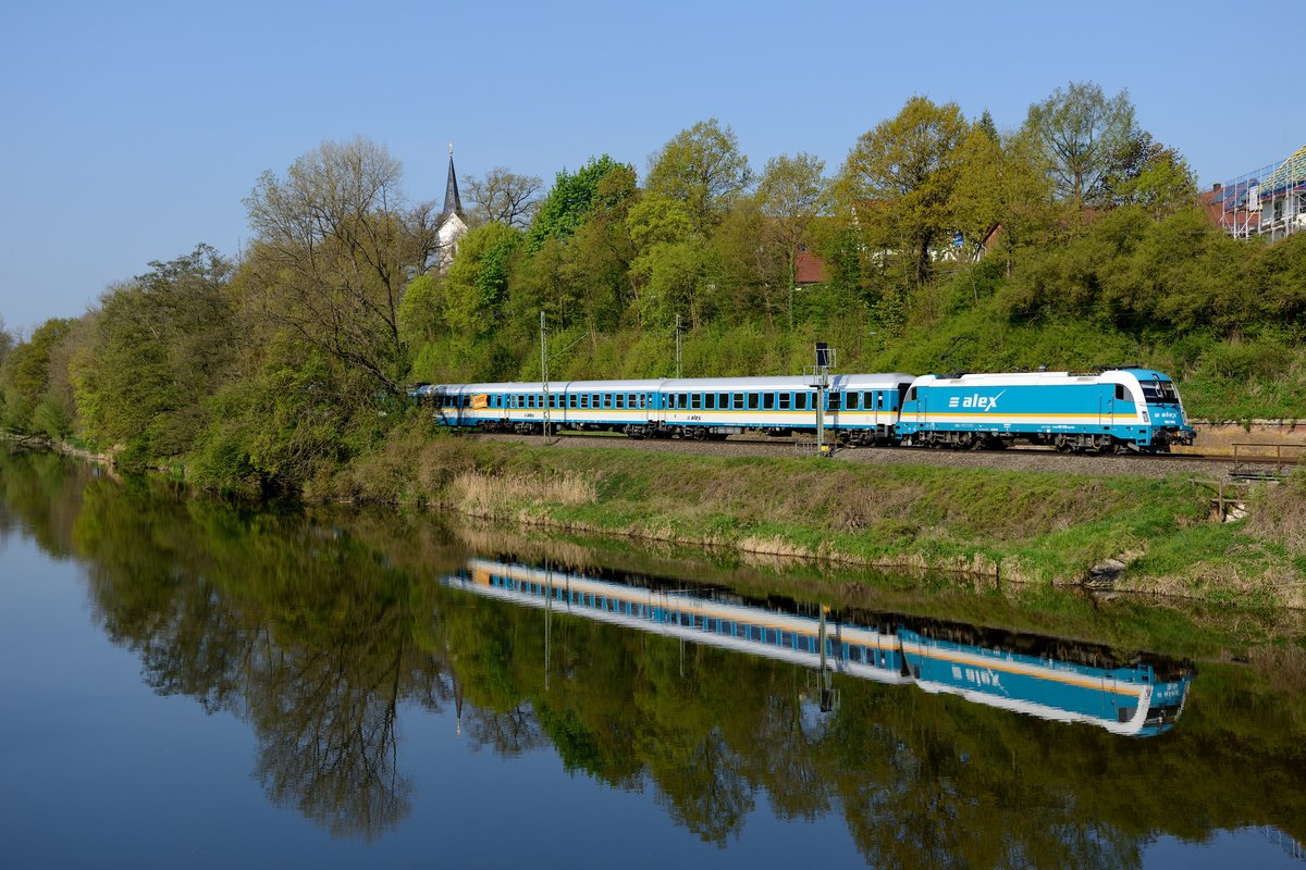 Die Alex-Züge der Vogtlandbahn erfreuen zumeist durch sehr guten Pflegezustand. Im ruhigen Wasser der Amper spiegelt sich 183 005 mit ihrem ALX 84104 auf der Fahrt nach Regensburg (Volkmannsdorf, 23. April 2014).